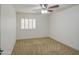 Bright bedroom with a ceiling fan, plush carpet, and plantation shutters on the window at 18249 W Mauna Loa Ln, Surprise, AZ 85388