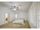 Bright bedroom features neutral carpeting, ceiling fan, shutters, and an open bathroom entrance at 18249 W Mauna Loa Ln, Surprise, AZ 85388