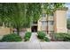 Inviting exterior view of a stucco apartment building entrance with mature trees and manicured landscaping at 18811 N 19Th Ave # 2020, Phoenix, AZ 85027
