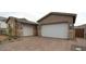 A beautiful home featuring a brick driveway leading to two white garage doors with stone accents on the exterior at 21612 W Pierson St, Buckeye, AZ 85396