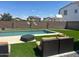 Backyard features a pristine swimming pool, artificial turf, lounge seating, and privacy wall at 23644 S 209Th Pl, Queen Creek, AZ 85142
