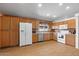 Bright kitchen with light wood cabinets, white appliances, and laminate flooring at 2467 E Winchester Pl, Chandler, AZ 85286