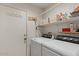 Functional laundry room with modern washer and dryer, storage shelves, and convenient access to the exterior at 2467 E Winchester Pl, Chandler, AZ 85286