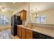 Kitchen area featuring stainless sink, granite countertops, wood cabinets, black appliances and tiled floors at 25860 N 47Th Pl, Phoenix, AZ 85050