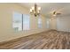 Bright living room with wood-look tile flooring, chandelier, and multiple windows offering natural light at 25860 N 47Th Pl, Phoenix, AZ 85050