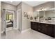 Bathroom with dual sink vanity, dark wood cabinets, and views of living room at 26049 N 104Th Pl, Scottsdale, AZ 85255