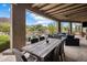 Spacious covered patio featuring a rustic wooden table and ample seating, overlooking a pool and lush landscaping at 26049 N 104Th Pl, Scottsdale, AZ 85255