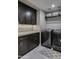 Well-organized laundry room with dark cabinetry, quartz countertops, and modern appliances at 26049 N 104Th Pl, Scottsdale, AZ 85255