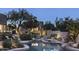 Inviting pool with stone accents, lounge chairs, mature trees, and lush landscaping at 26049 N 104Th Pl, Scottsdale, AZ 85255