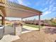 Backyard with a covered patio, built-in grill, desert landscaping, and green turf at 30909 N 27Th Ave, Phoenix, AZ 85085
