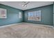 Bright bedroom with neutral carpet, recessed lights, light blue accent wall, and white shutters at 30909 N 27Th Ave, Phoenix, AZ 85085