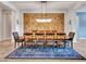 Elegant dining area with a large table, decorative rug, a stone accent wall, and chandelier at 30909 N 27Th Ave, Phoenix, AZ 85085