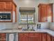 A kitchen featuring granite countertops, wooden cabinets, a stainless steel sink, and a view from the window at 30909 N 27Th Ave, Phoenix, AZ 85085
