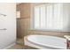 A bright bathroom features a soaking tub and a tiled shower under a window with shutters at 31604 N 19Th Ave, Phoenix, AZ 85085