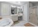 Bright bathroom features a soaking tub, walk-in shower, and dual sinks with white cabinets and neutral tile floors at 3603 E Salter Dr, Phoenix, AZ 85050