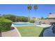 Backyard showcasing a sparkling pool, artificial turf, and mature landscaping at 3612 W Charlotte Dr, Glendale, AZ 85310