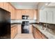 Well-equipped kitchen featuring wood cabinetry, granite countertops, and black appliances at 3820 E Mcdowell Rd # 102, Phoenix, AZ 85008