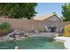 Backyard pool includes rock waterfall, chairs, and grill at 3898 E San Remo Ave, Gilbert, AZ 85234