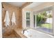 Bright bathroom featuring a standalone tub under a large window and textured stone accents at 4916 E Flower St, Phoenix, AZ 85018