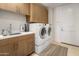 Bright laundry room with washer, dryer, upper and lower cabinets, sink, and door with neutral color scheme at 5533 E Stella Ln, Paradise Valley, AZ 85253