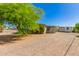 Exterior view of home with gravel yard featuring mature tree and covered patio at 5627 E Covina Rd, Mesa, AZ 85205