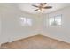 Bright bedroom with neutral carpet, ceiling fan, and windows providing natural light at 6043 E Des Moines St, Mesa, AZ 85205