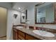 A well-lit bathroom features double sinks with granite countertops and decorative mirrors enhancing the space at 7015 W Behrend Dr, Glendale, AZ 85308
