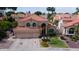 Attractive two-story home with red tile roof, three-car garage, palm trees and lush landscaping at 7015 W Behrend Dr, Glendale, AZ 85308