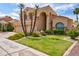 A charming home with palm trees, meticulously maintained lawn and landscape beds with yellow flowers at 7015 W Behrend Dr, Glendale, AZ 85308