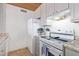 A bright kitchen featuring sleek white appliances, a smooth cooktop, and granite countertops for modern appeal at 8055 E Thomas Rd # B208, Scottsdale, AZ 85251