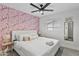 Modern bedroom featuring a flamingo accent wall, plush white bedding, and a ceiling fan at 8707 E Clarendon Ave, Scottsdale, AZ 85251