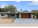 Charming single story home with desert landscaping, gray stucco, and a modern wood grain garage door at 8707 E Clarendon Ave, Scottsdale, AZ 85251