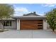 Close up of a modern home featuring a sleek, wood-grain garage door with glass inserts and gray stucco at 8707 E Clarendon Ave, Scottsdale, AZ 85251
