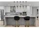 Modern kitchen features a center island with seating, pendant lights, gray and white cabinets, and stylish backsplash at 8707 E Clarendon Ave, Scottsdale, AZ 85251
