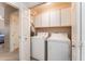 Laundry room with full-size washer and dryer plus overhead storage cabinets at 8880 E Paraiso Dr # 118, Scottsdale, AZ 85255