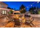 Backyard view of a home at dusk, with an outdoor kitchen, a fire pit, string lights overhead, and manicured landscaping at 1379 S Claiborne Ave, Gilbert, AZ 85296