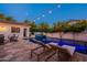Backyard pool and patio area with modern lounge chairs, string lights, and a lush green privacy fence at 1379 S Claiborne Ave, Gilbert, AZ 85296