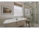 Classic white bathroom with freestanding tub, a frameless glass shower, and a frosted window for privacy at 1379 S Claiborne Ave, Gilbert, AZ 85296