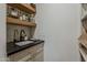 Close-up of a sink area with matte black faucet in the butler's pantry with floating shelves and stylish backsplash at 1379 S Claiborne Ave, Gilbert, AZ 85296