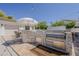 Outdoor kitchen area with a built-in stainless steel grill and convenient bar seating at 1379 S Claiborne Ave, Gilbert, AZ 85296