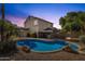 Backyard at dusk featuring a large pool, outdoor kitchen, and fire pit, ideal for entertaining at 2545 E Harrison Ct, Gilbert, AZ 85295