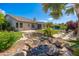 Backyard with rock waterfall feature and lush landscaping, with a pool in the distance at 6428 E Nisbet Rd, Scottsdale, AZ 85254