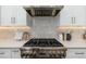 Close up of a gas range and tile backsplash with stainless steel vent hood at 6428 E Nisbet Rd, Scottsdale, AZ 85254