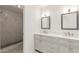 Bright bathroom featuring dual sinks, a vanity, and a tiled shower at 702 W Sequoia Dr, Phoenix, AZ 85027