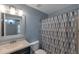 Well-lit bathroom showcasing a vanity with a sink, toilet, and shower with a patterned curtain at 8524 S 49Th Ln, Laveen, AZ 85339