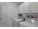 Functional laundry room with white cabinets, washer, dryer, and ample storage space at 8524 S 49Th Ln, Laveen, AZ 85339