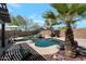 Backyard pool featuring a rock waterfall, palm trees, and adjacent patio area for outdoor enjoyment at 8524 S 49Th Ln, Laveen, AZ 85339