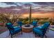 Cozy backyard features an outdoor fire pit surrounded by chairs at sunset at 10934 E La Verna Way, Scottsdale, AZ 85262