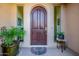 Elegant wooden front door flanked by sidelights and potted plants at 10934 E La Verna Way, Scottsdale, AZ 85262