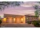 Tiled roof home with three-car garage and desert landscaping at dusk at 10934 E La Verna Way, Scottsdale, AZ 85262